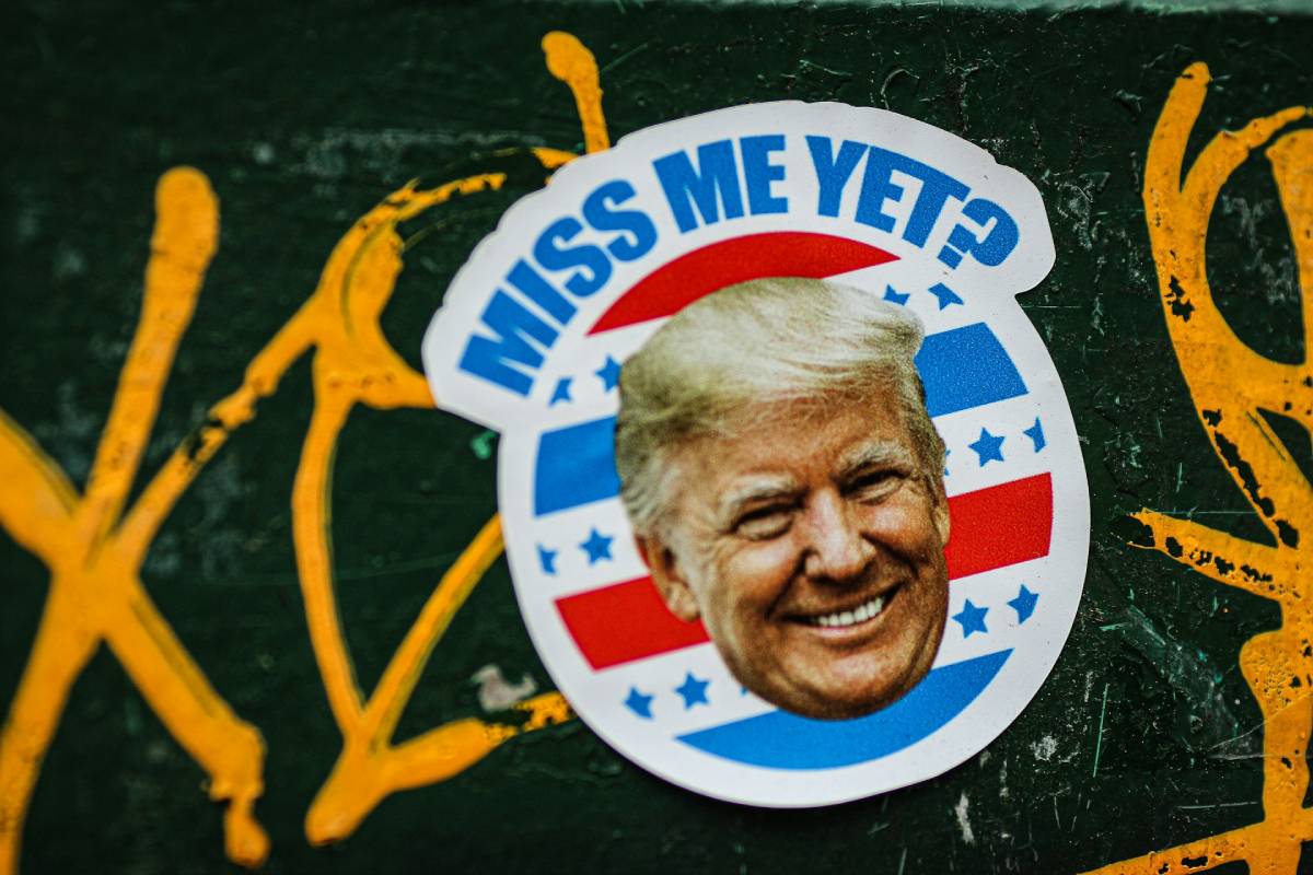 Wlepka na murze: Zdjęcie uśmiechniętej twarzy Trumpa z podpisem: Miss me yet?